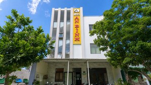 Un bâtiment d’hôtel avec une enseigne jaune bien visible, de nombreuses fenêtres et un espace d’entrée abrité où sont garées des motos.