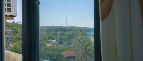 A view from a window overlooking a residential area with houses, trees, and a clear sky.