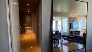 Un couloir au plancher de bois menant à une salle à manger équipée d’une table et de chaises.