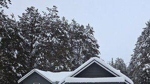 Une maison à deux étages avec un garage, entourée d’arbres couverts de neige.