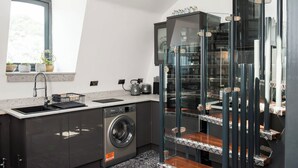 Una cocina moderna con lavadora y secadora integradas, una ventana con plantas y una escalera de cristal.