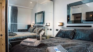 Una habitación de hotel moderna con una cama grande, un escritorio pequeño y un espejo.
