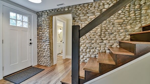 Una escalera con pared de piedra, peldaños de madera y barandilla de metal.