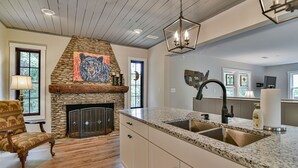 Una cocina con chimenea de piedra, encimeras de granito y techo de madera.