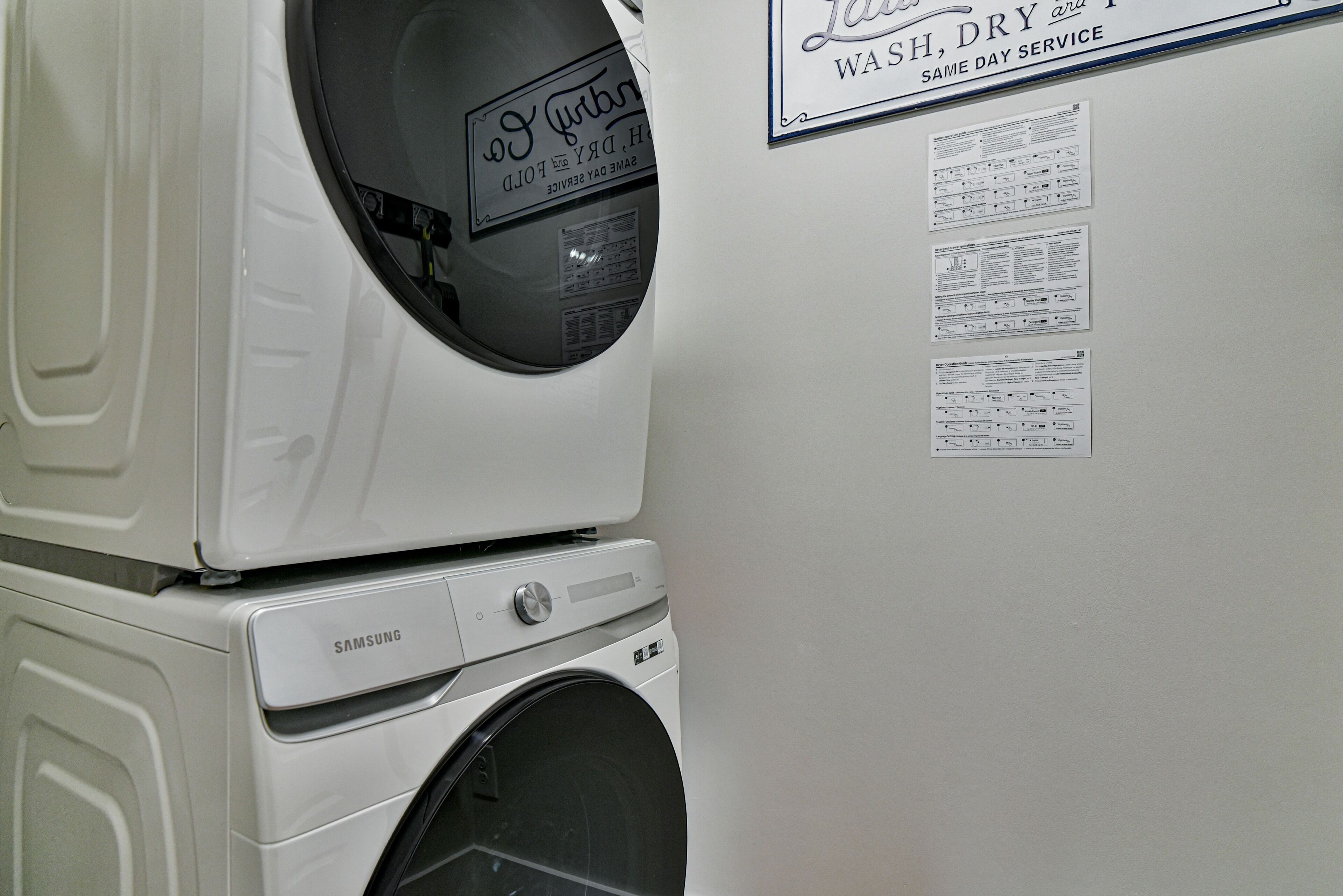 A stacked washer and dryer unit with a wall sign above indicating same day service.