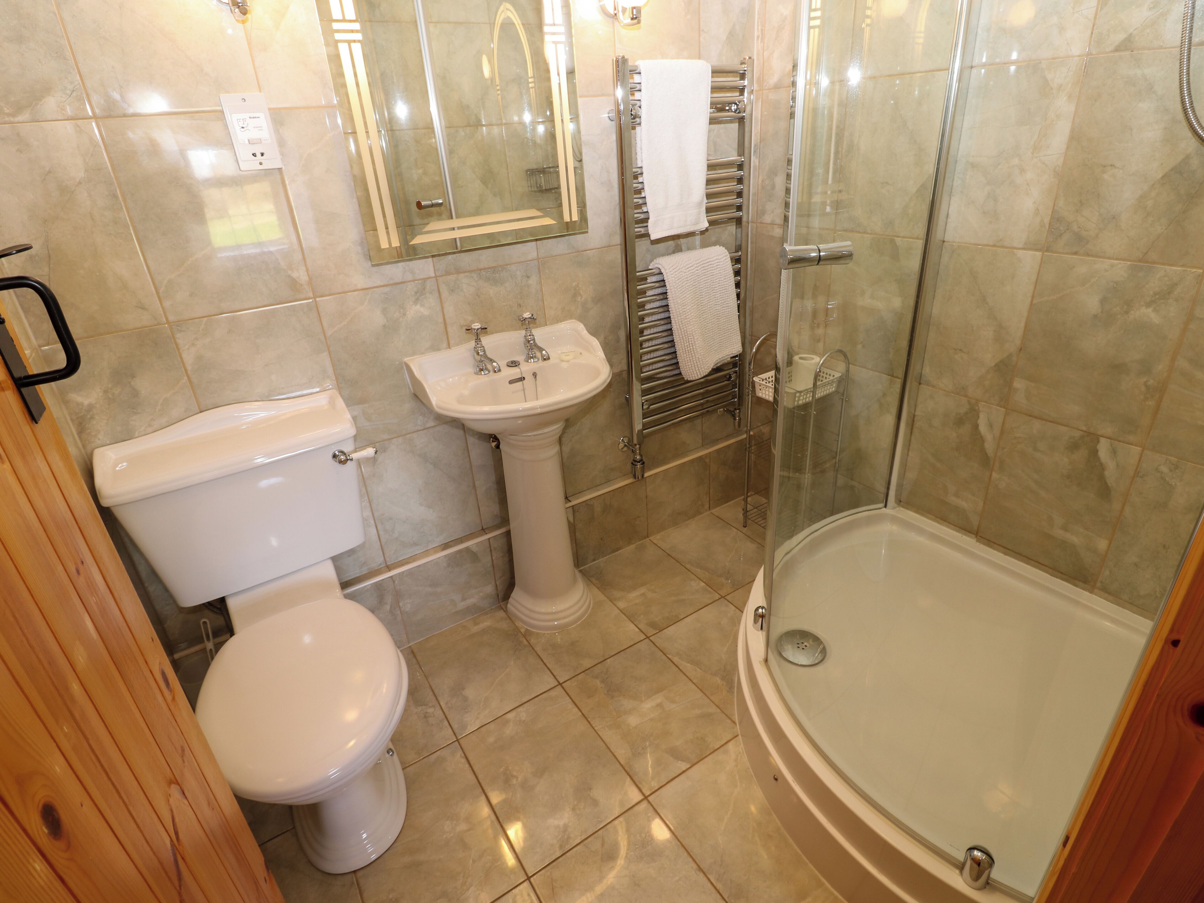 Ein Badezimmer mit Toilette, Waschbecken auf Säule und einer Duschkabine.