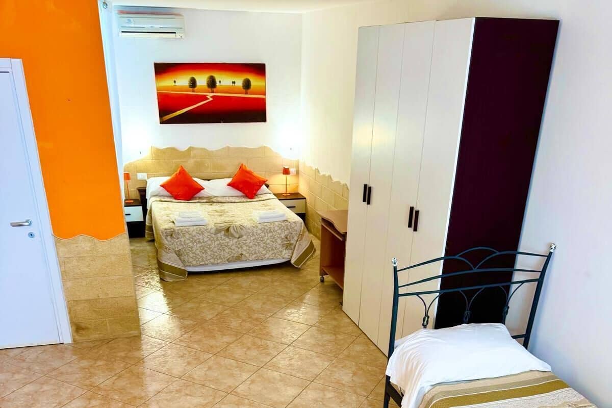 A hotel room with two beds, a wardrobe, and a painting on the wall.