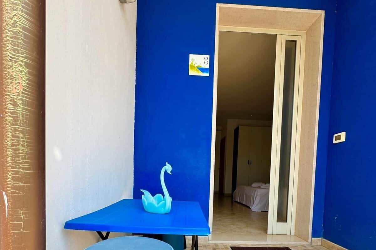 A room with a blue wall, a small table with a blue stool, and a door leading to another room.