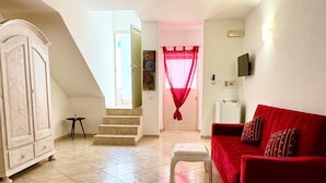 A spacious living room with a red sofa, a white cabinet, and a staircase leading to another room. - Residence Luxora (Melendugno)