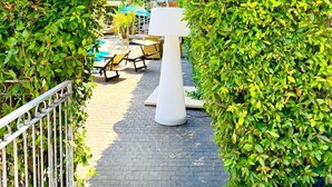 A pathway leading to a pool area with a white lamp post and outdoor seating. - Residence Luxora (Melendugno)