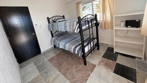 A small, clean room with a bed, a wardrobe, and a window with curtains. - Ocen view spacious villa (Acapulco de Juárez)