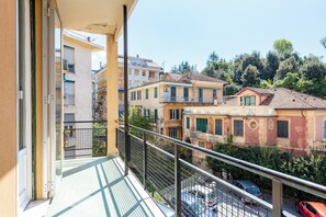 Un balcón con vista a una zona residencial, con edificios y coches aparcados.
