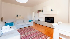 Un soggiorno moderno con divano, televisione e zona pranzo.