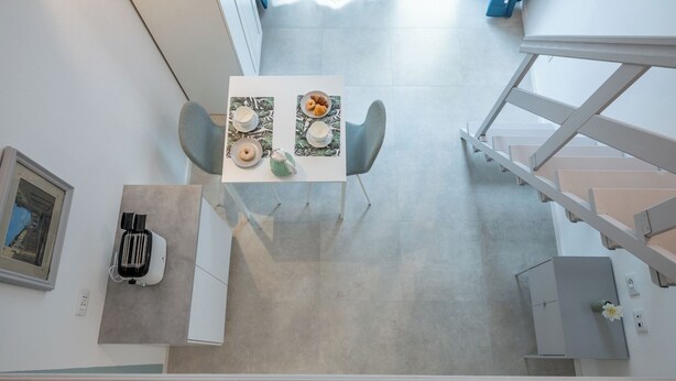A modern kitchen with a dining table set for two, a toaster, and a framed picture on the wall.