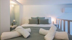 A bedroom with a bed, pillows, a nightstand, a lamp, and a window.