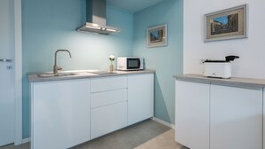 A modern kitchen with a stainless steel sink, a microwave, and a toaster. There are two framed pictures on the wall.