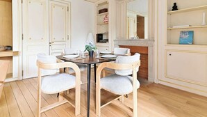 Comedor con una mesa redonda, cuatro sillas, chimenea y un espejo sobre la repisa.
