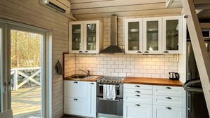 Eine kleine Küche mit weißen Schränken, einer Holz Arbeitsplatte und einem eingebauten Backofen.