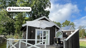 Eine Holzhütte mit einer Terrasse, einem Essbereich und Solaranlagen auf dem Dach.