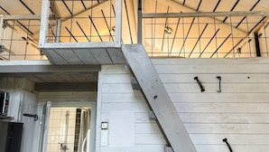 Eine mehrstöckige Holzkonstruktion mit Treppe, Metallgeländern und einer Duschkabine.