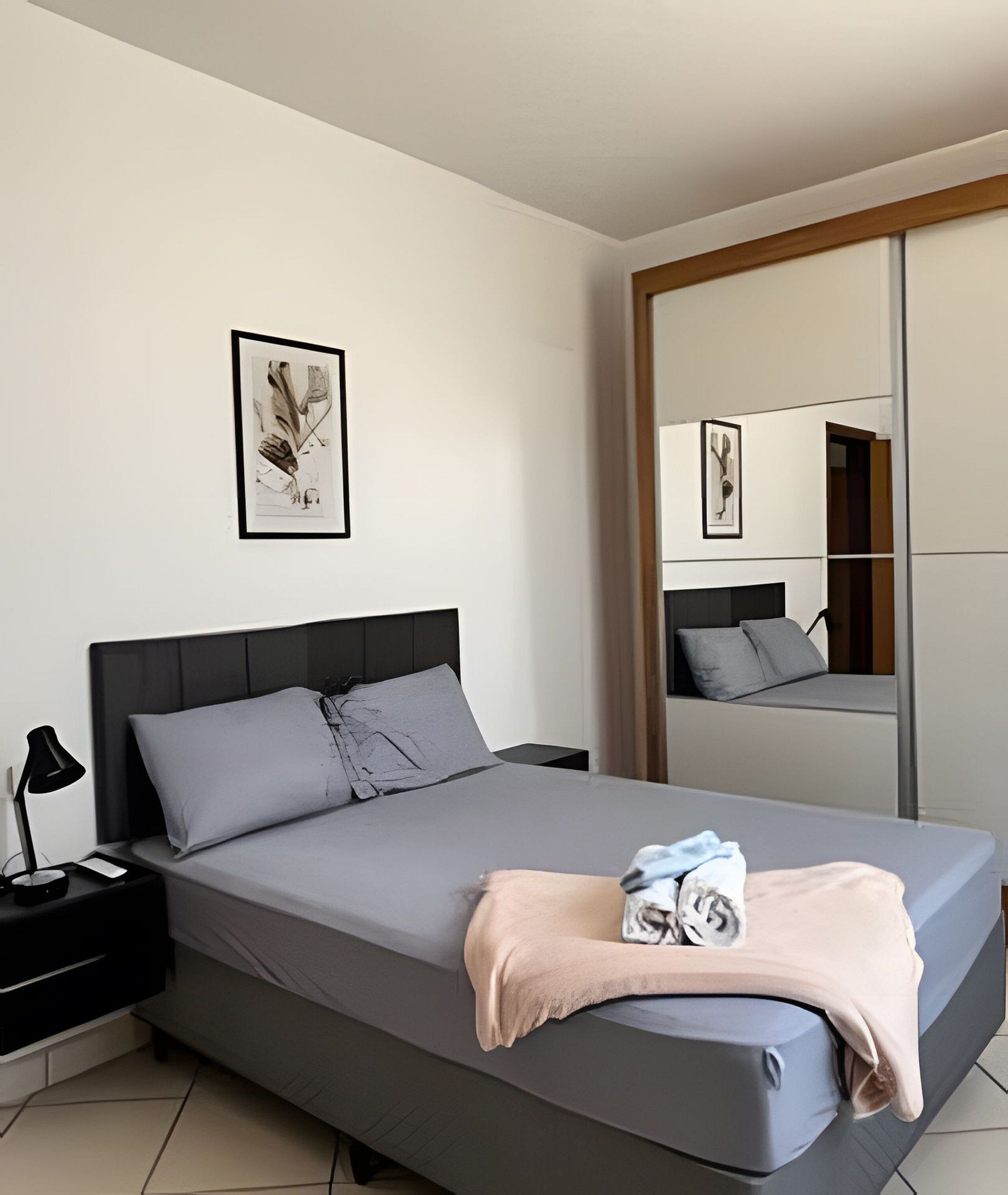 Une chambre à coucher moderne avec un lit, une table de chevet et un grand miroir.
