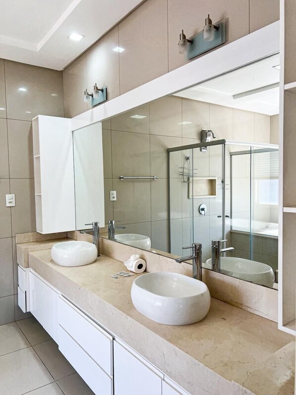 Un baño moderno con dos lavamanos, un espejo grande y una cabina de ducha de vidrio.