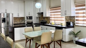 A modern kitchen with white cabinets, stainless steel appliances, and a dining area with a glass table and chairs.