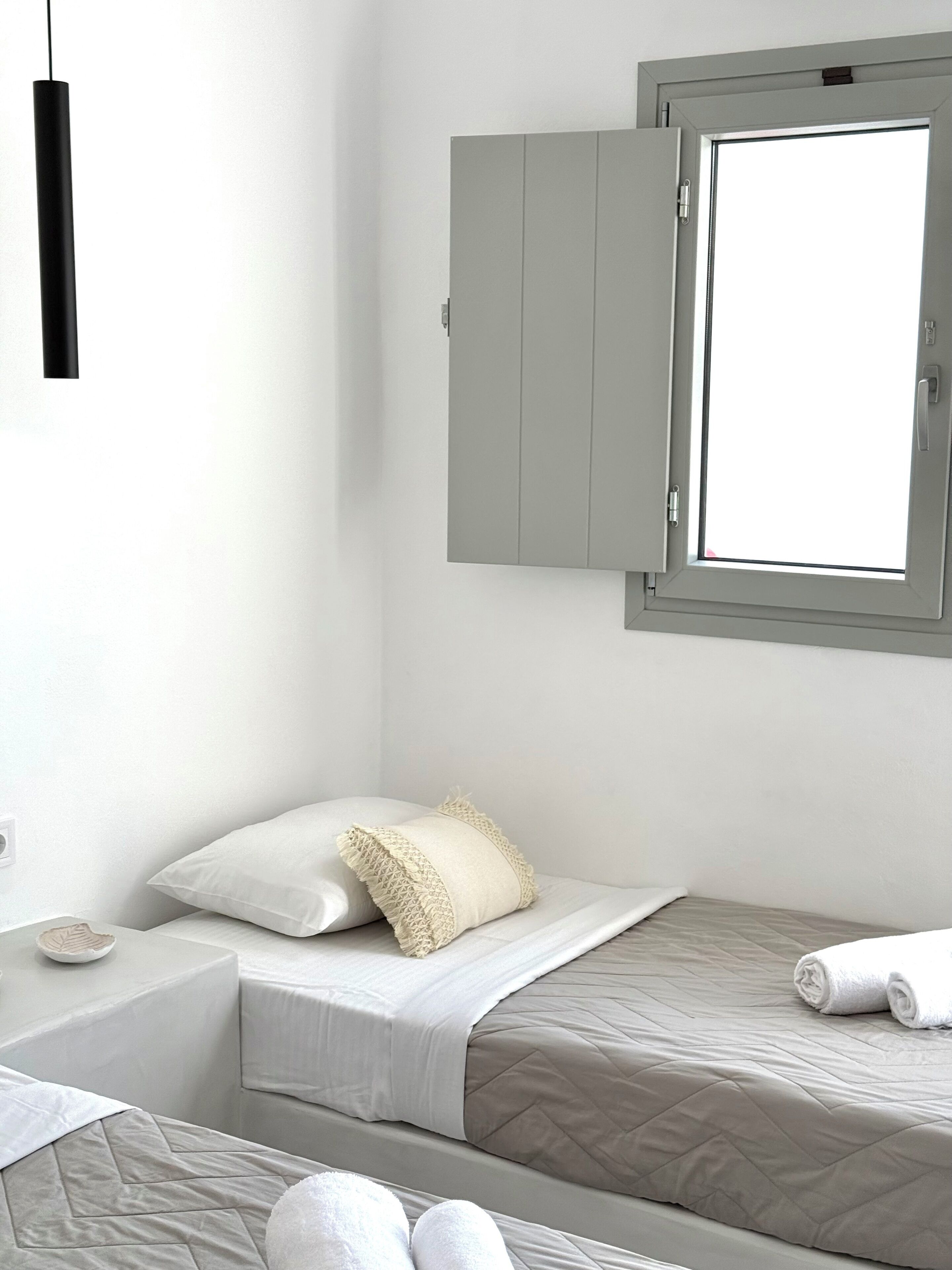 A bedroom with a bed, a window with a view, and a bedside table with a lamp.