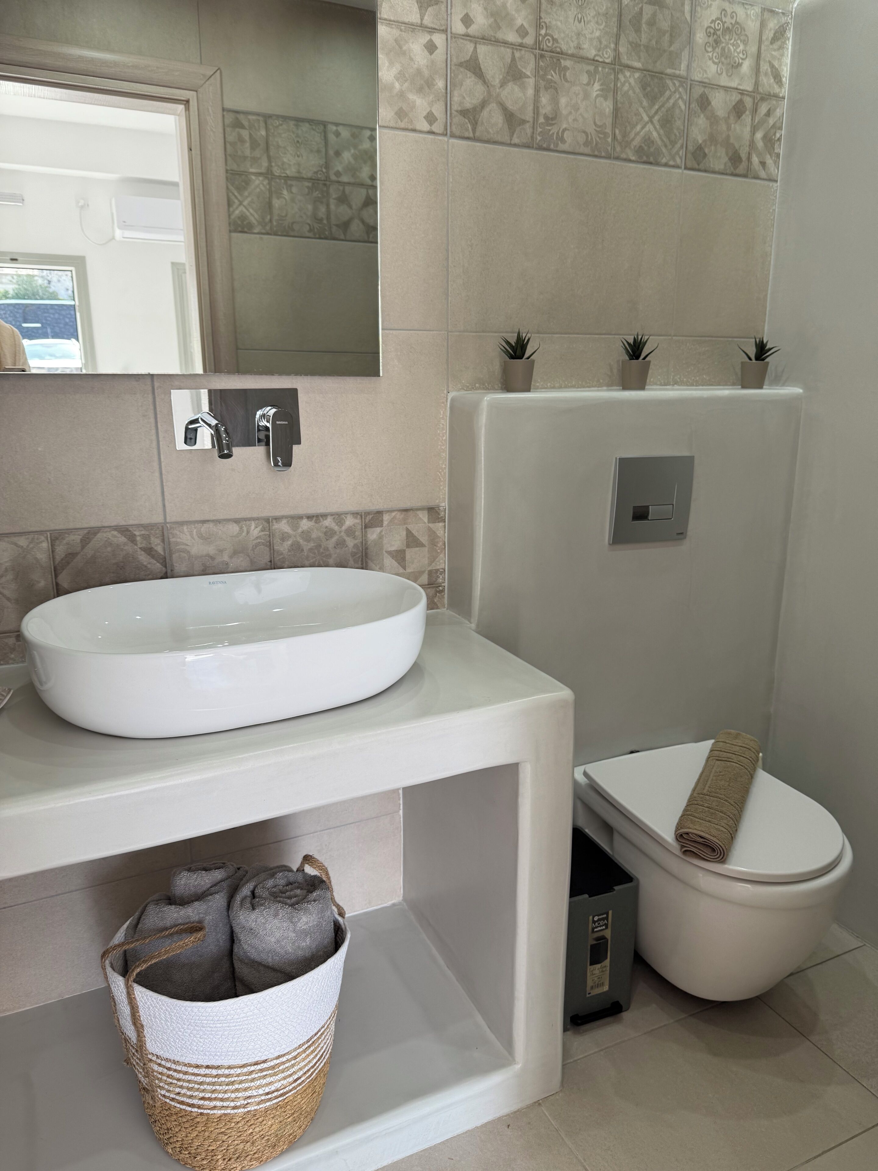 A bathroom with a white sink, a mirror, a toilet, and a shower area.