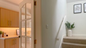 Eine Küche mit Holzschränken, einem Fenster und einer Treppe mit beigem Teppich.