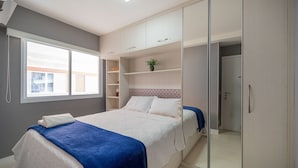 Un dormitorio con cama, armario y ventana.