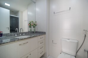 A bathroom with a granite countertop sink, a toilet with a shower hose, and a mirror above the sink. - Cf06 apto 3 quartos 150m Praia do Forte (Cabo Frio)