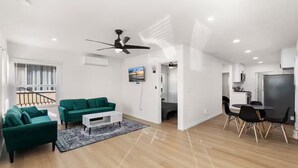 A modern living room with a green sofa set, a coffee table, and a dining area with a table and chairs.