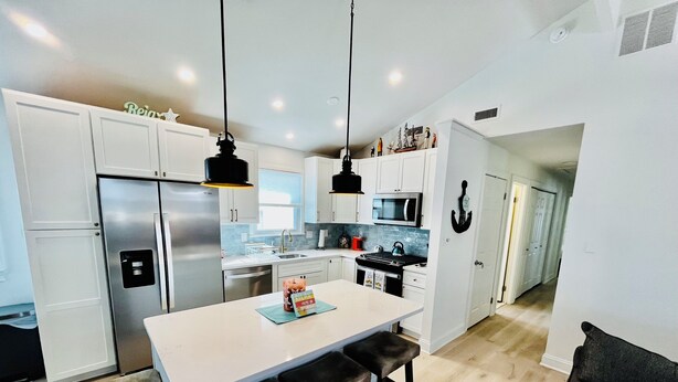 A modern kitchen with white cabinets, stainless steel appliances, and a central island with bar stools.