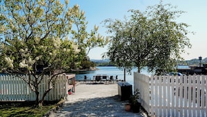 Un espace patio avec vue sur un lac, une clôture blanche en bois et du mobilier d’extérieur.