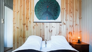 Une chambre avec un mur en bois, un lit avec une literie blanche et une table de chevet avec une lampe.