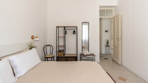 Una camera da letto con un letto, una sedia, un tavolino, uno specchio e un armadio.