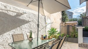 An outdoor patio with a glass table, chairs, a potted plant, and a decorative fence. - Mondello Sea Life Duplex by Wonderful Italy (Palermo)
