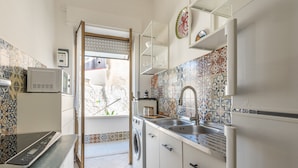 Una cucina compatta con lavatrice, forno a microonde e lavello.