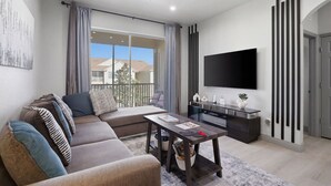 Ein modernes Wohnzimmer mit Sofa, Couchtisch, Fernseher und Balkonblick.