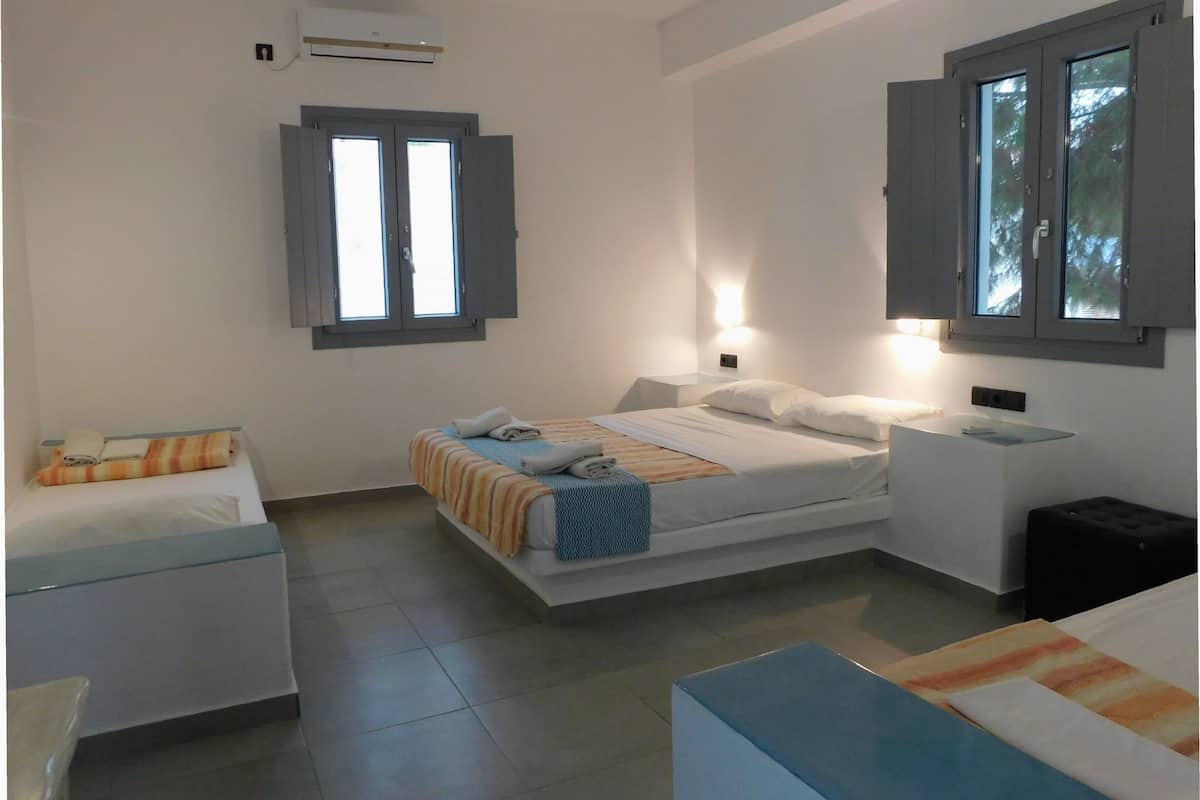 Une chambre d’hôtel comprenant un lit, des tables de chevet, un petit coin salon et une fenêtre avec des rideaux.