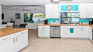 Una cocina moderna con armarios blancos, encimera de madera y vistas a una piscina.