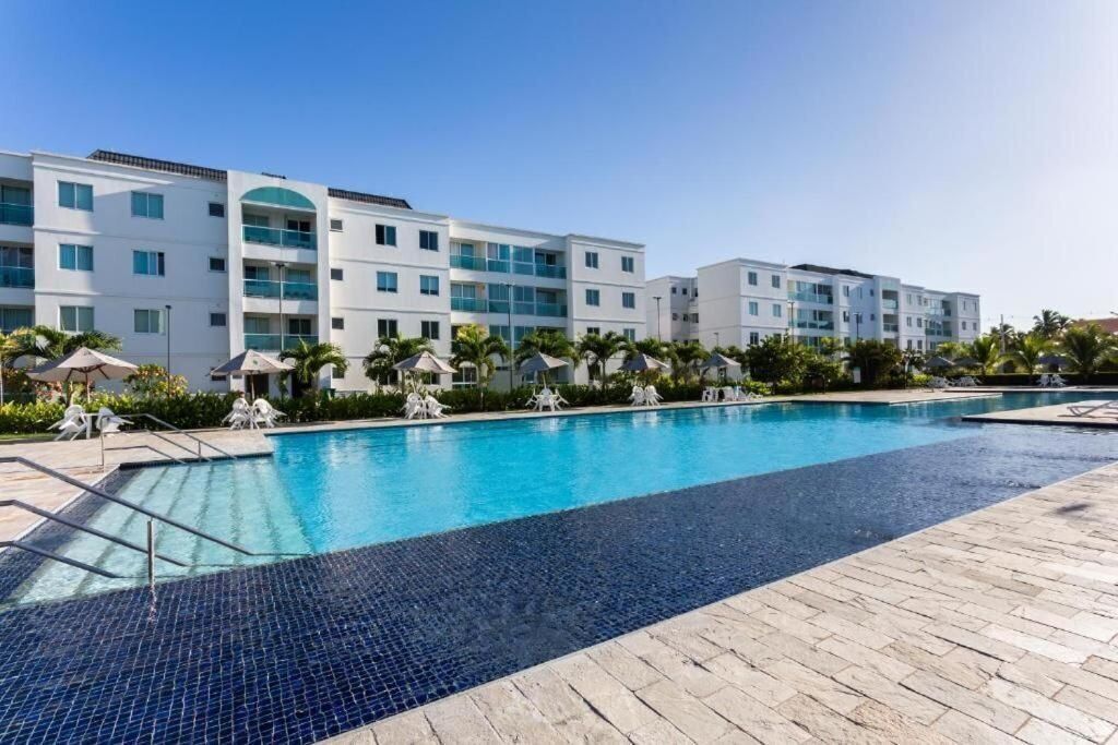 Un hotel moderno con piscina, varios balcones y palmeras.