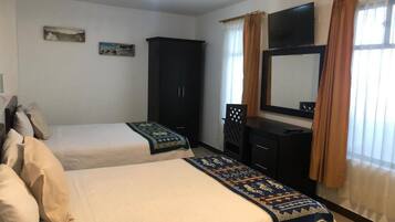 Habitación de hotel con dos camas, un armario, un escritorio, un televisor y una ventana con cortinas.