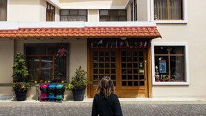 The exterior of MakroZ Colonial Hotel with a tiled roof, potted plants, and a signboard. - Hotel Makroz Colonial (Latacunga)