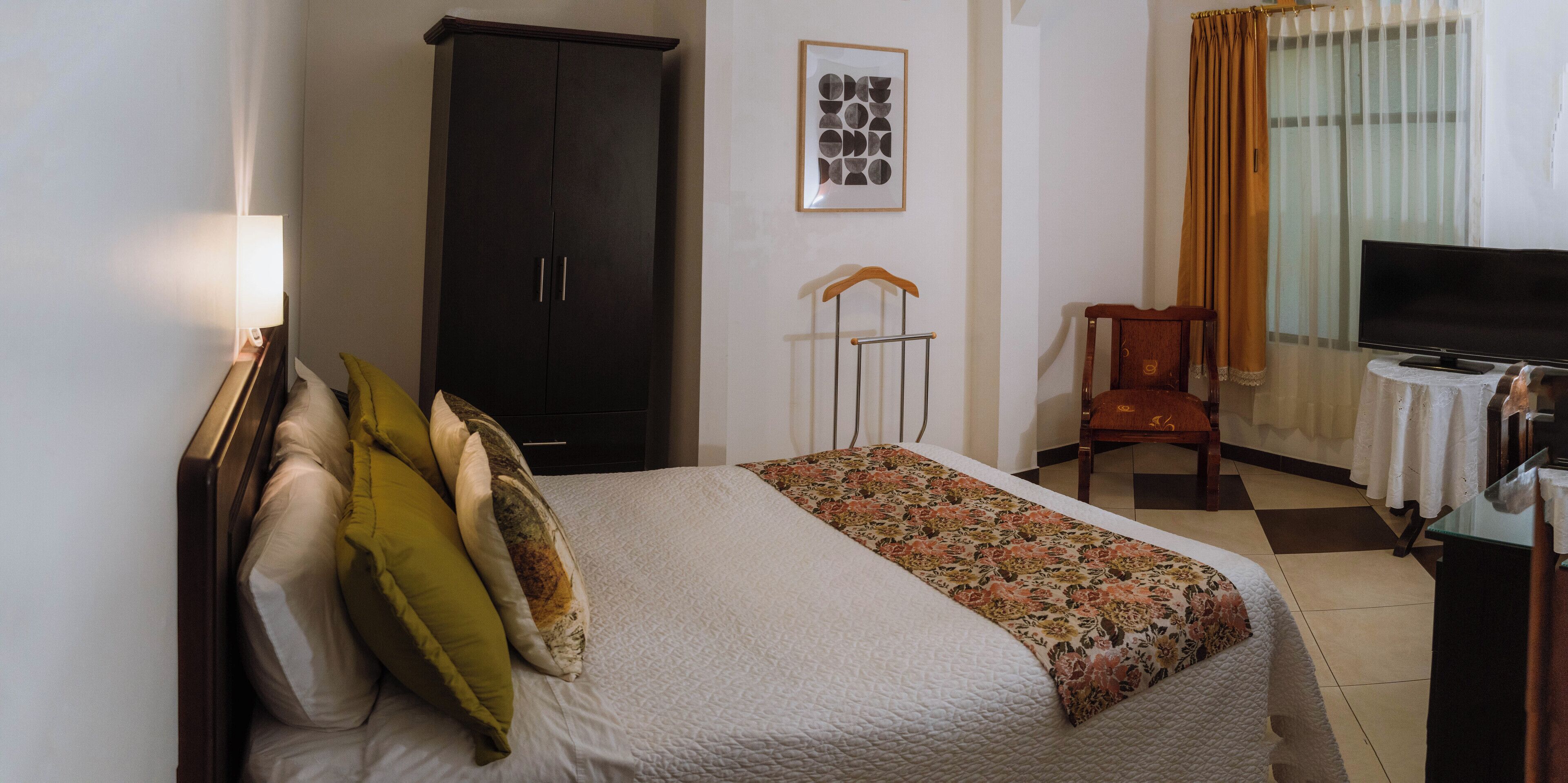 A hotel room with a bed, a wardrobe, a television, and a chair.