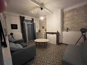 Un salon avec un canapé, une table ronde, une cheminée et un mur en pierre.