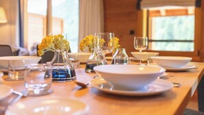 Una mesa de comedor dispuesta con platos, tazones y vasos blancos, y pequeños jarrones con flores amarillas.