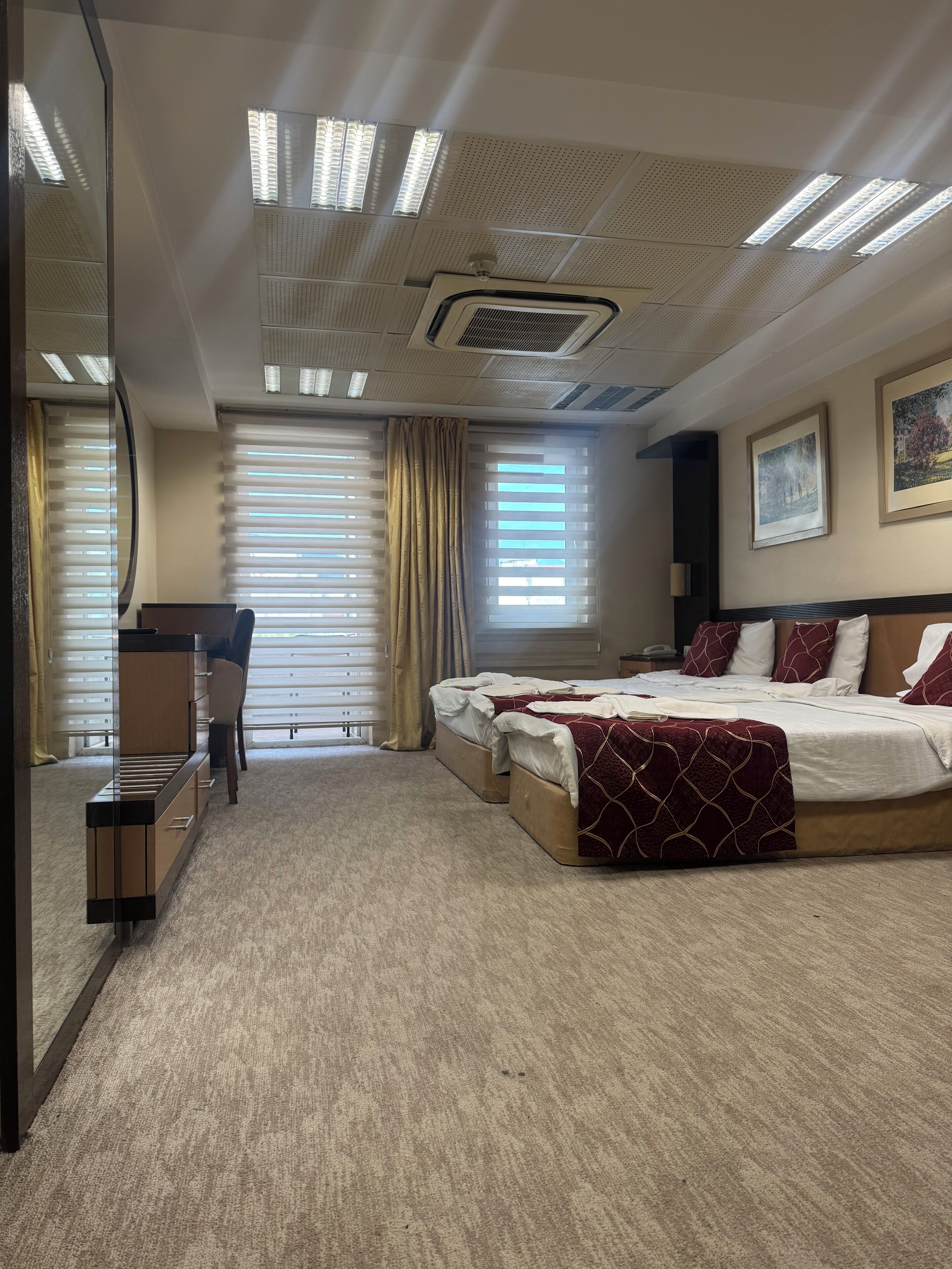 A hotel room with a large bed, a desk, and a mirror.