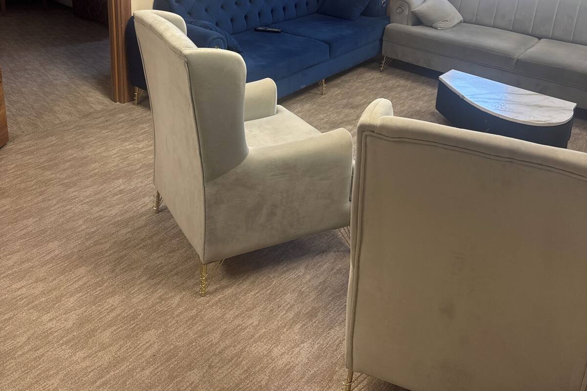 A hotel room with a blue sofa, a white armchair, a grey sofa, and a small table.